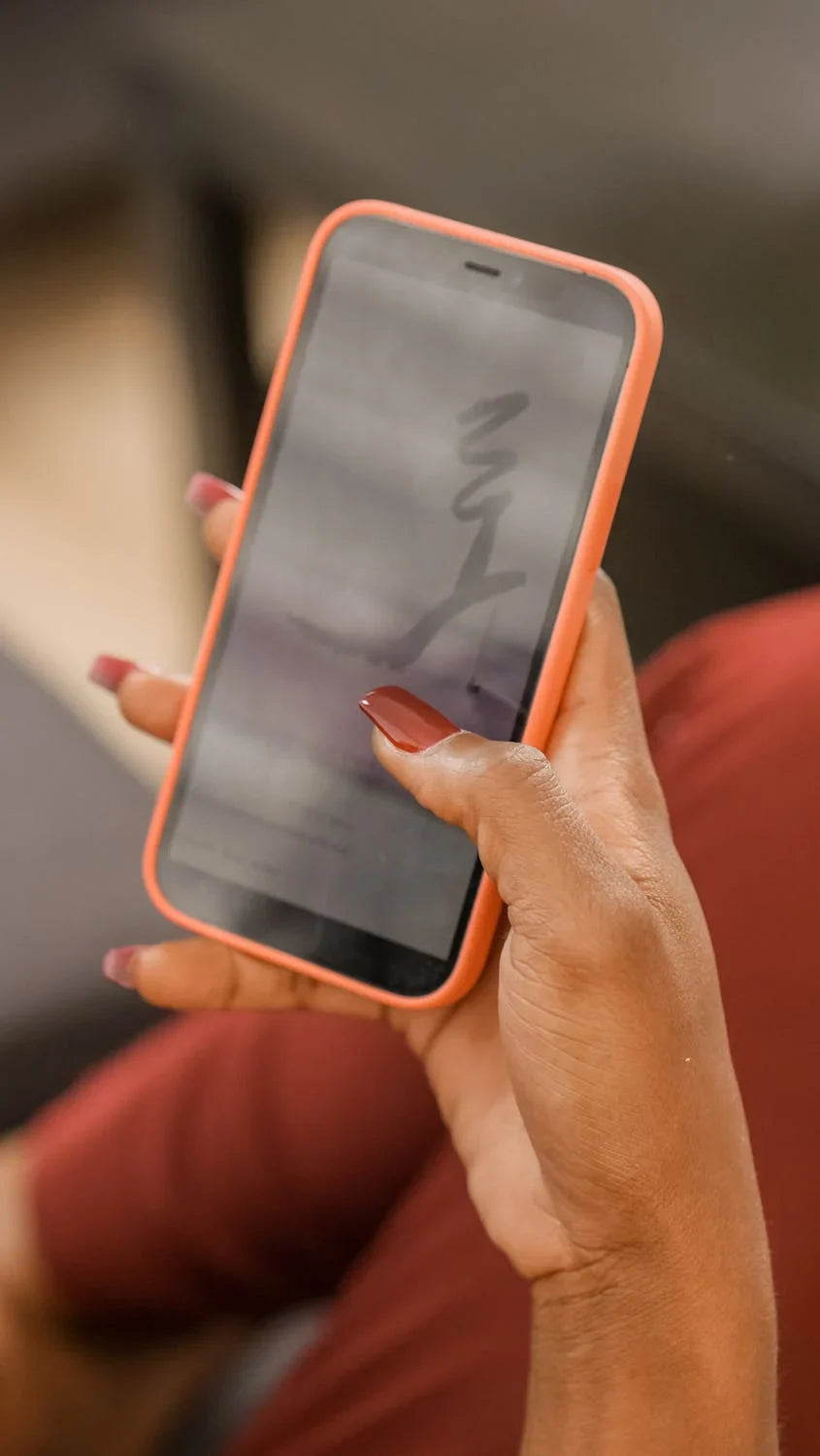 A person holding a phone with an orange phone case.