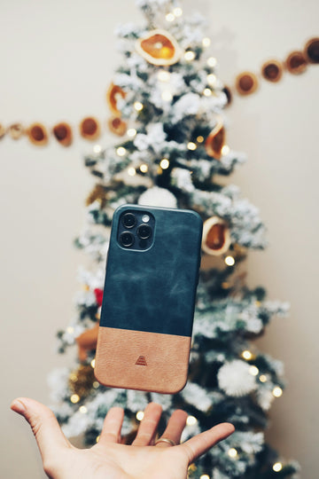 A phone floating on top of a hand with a Christmas tree in the background. 